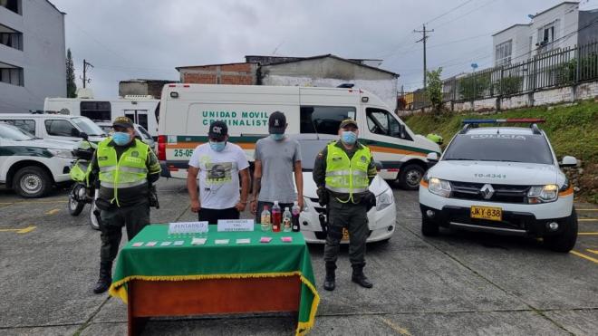 Dos capturados- policías custodiando-alucinógenos incautados