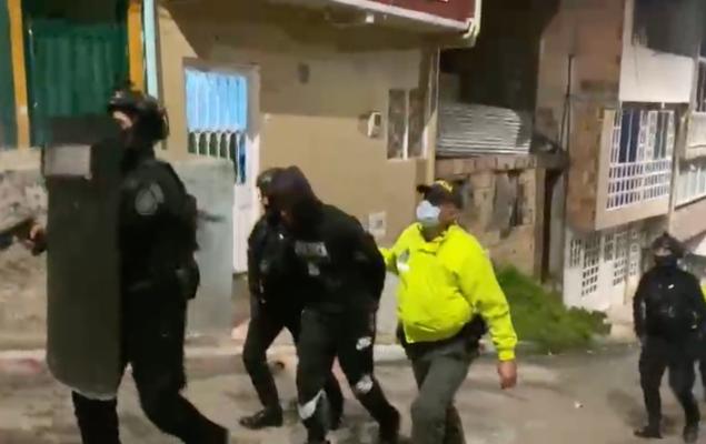 Policías trasladando a uno de los capturados por una de las calles de la localidad de Usme